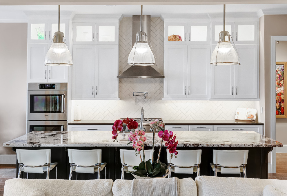 Foto de cocina costera con puertas de armario blancas, salpicadero blanco, salpicadero de azulejos de cerámica, electrodomésticos de acero inoxidable y encimeras negras