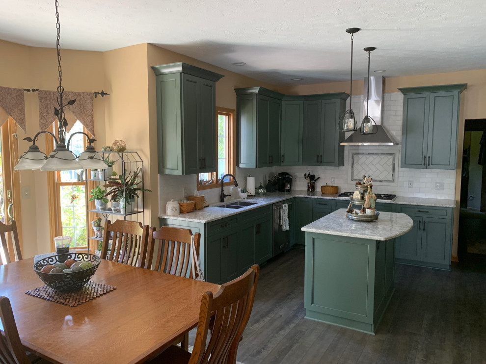 Eat-in kitchen - mid-sized l-shaped medium tone wood floor and brown floor eat-in kitchen idea in Cleveland with an undermount sink, shaker cabinets, green cabinets, quartz countertops, white backsplash, subway tile backsplash, stainless steel appliances, an island and white countertops