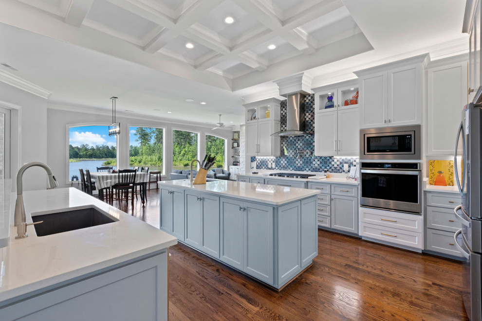 Eat-in kitchen - large coastal dark wood floor, brown floor and vaulted ceiling eat-in kitchen idea in Raleigh with a single-bowl sink, shaker cabinets, white cabinets, quartz countertops, multicolored backsplash, ceramic backsplash, stainless steel appliances, two islands and white countertops