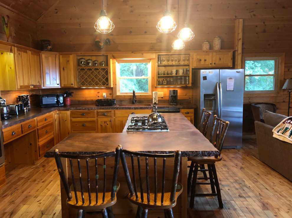 Rustik inredning av ett mellanstort brun brunt kök, med en rustik diskho, skåp i shakerstil, skåp i ljust trä, bänkskiva i betong, gult stänkskydd, stänkskydd i trä, rostfria vitvaror, ljust trägolv och en köksö