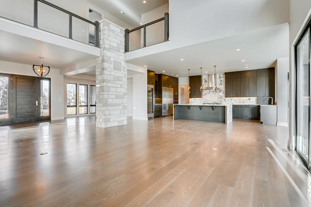 Inspiration for a huge contemporary l-shaped medium tone wood floor and brown floor open concept kitchen remodel in Denver with flat-panel cabinets, dark wood cabinets, granite countertops, white backsplash, stainless steel appliances, an island and white countertops