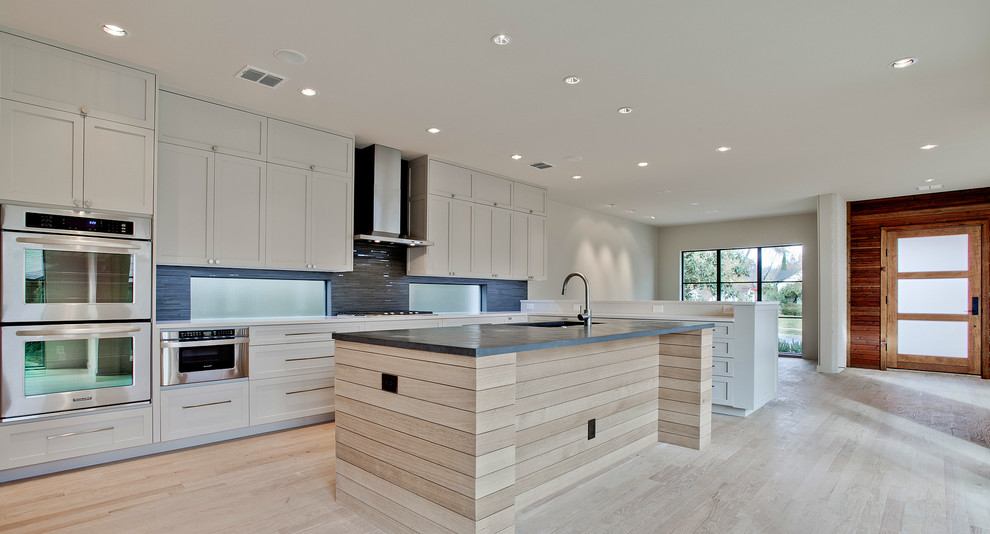 Photo of a medium sized contemporary single-wall kitchen/diner in Austin with shaker cabinets, white cabinets, composite countertops, blue splashback, ceramic splashback, stainless steel appliances, light hardwood flooring and an island.