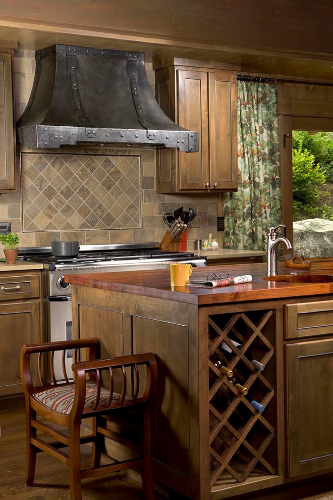 Aménagement d'une cuisine montagne en bois brun avec un placard avec porte à panneau encastré, un plan de travail en bois, une crédence multicolore, un électroménager en acier inoxydable et une crédence en ardoise.