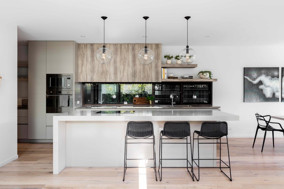 Zweizeilige, Mittelgroße Moderne Wohnküche mit integriertem Waschbecken, flächenbündigen Schrankfronten, Rückwand-Fenster, schwarzen Elektrogeräten, hellem Holzboden, Kücheninsel und weißer Arbeitsplatte in Sydney