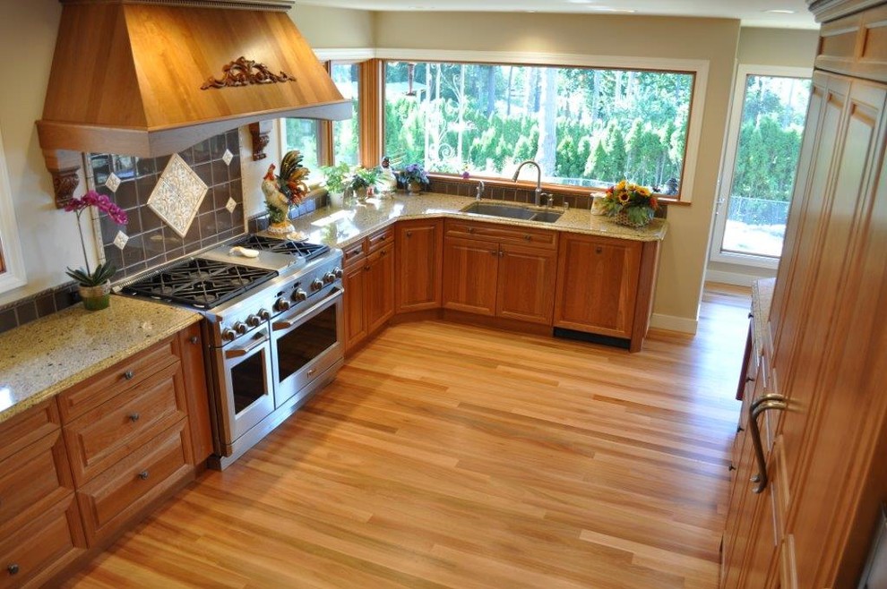 Enclosed kitchen - mid-sized traditional u-shaped light wood floor enclosed kitchen idea in Seattle with a double-bowl sink, raised-panel cabinets, medium tone wood cabinets, granite countertops, gray backsplash, ceramic backsplash, stainless steel appliances and a peninsula