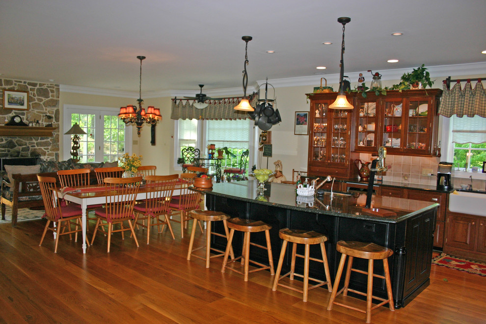 Huge elegant medium tone wood floor kitchen photo in Philadelphia with a farmhouse sink, glass-front cabinets, beige cabinets, granite countertops, beige backsplash and paneled appliances