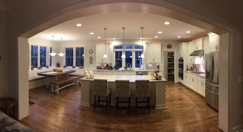 Inspiration for a large modern u-shaped light wood floor eat-in kitchen remodel in DC Metro with an undermount sink, beaded inset cabinets, white cabinets, solid surface countertops, white backsplash, ceramic backsplash, stainless steel appliances and an island