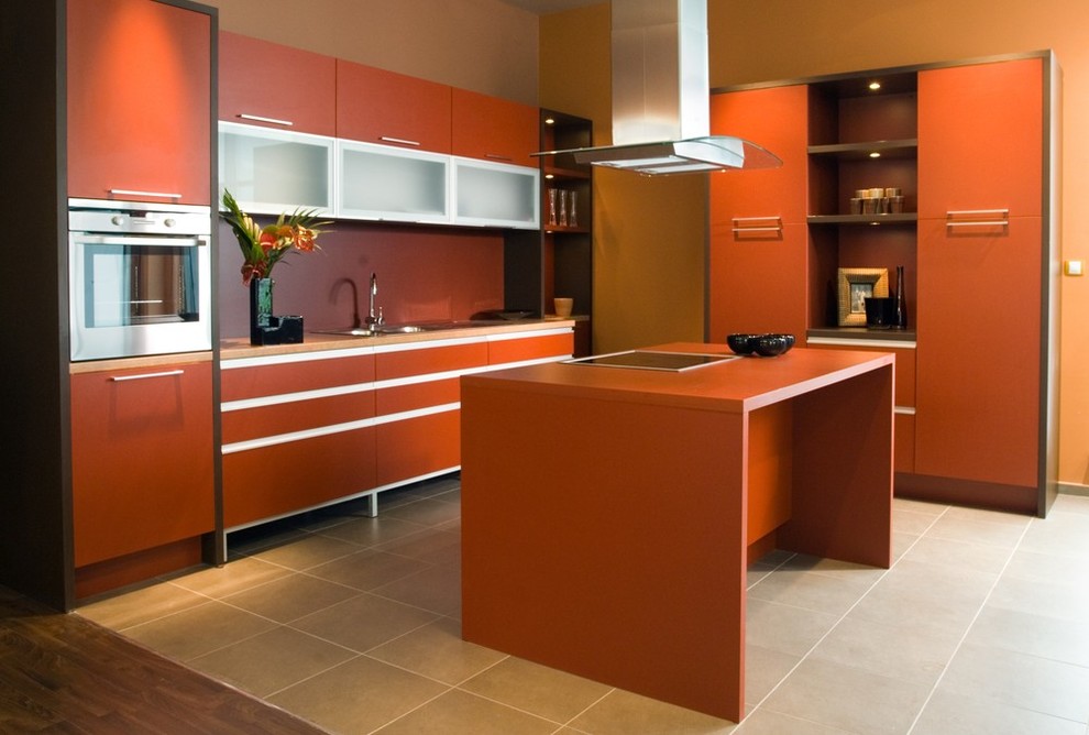 На фото: отдельная, угловая кухня среднего размера в современном стиле с двойной мойкой, плоскими фасадами, оранжевыми фасадами, столешницей из акрилового камня, техникой из нержавеющей стали, полом из керамогранита и островом с