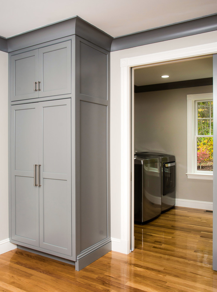 Example of a trendy light wood floor kitchen pantry design in Boston with an undermount sink, beaded inset cabinets, gray cabinets, solid surface countertops, white backsplash, subway tile backsplash, stainless steel appliances and an island