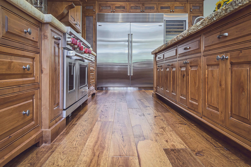Diseño de cocina clásica con puertas de armario de madera oscura, encimera de granito, suelo de madera en tonos medios y una isla