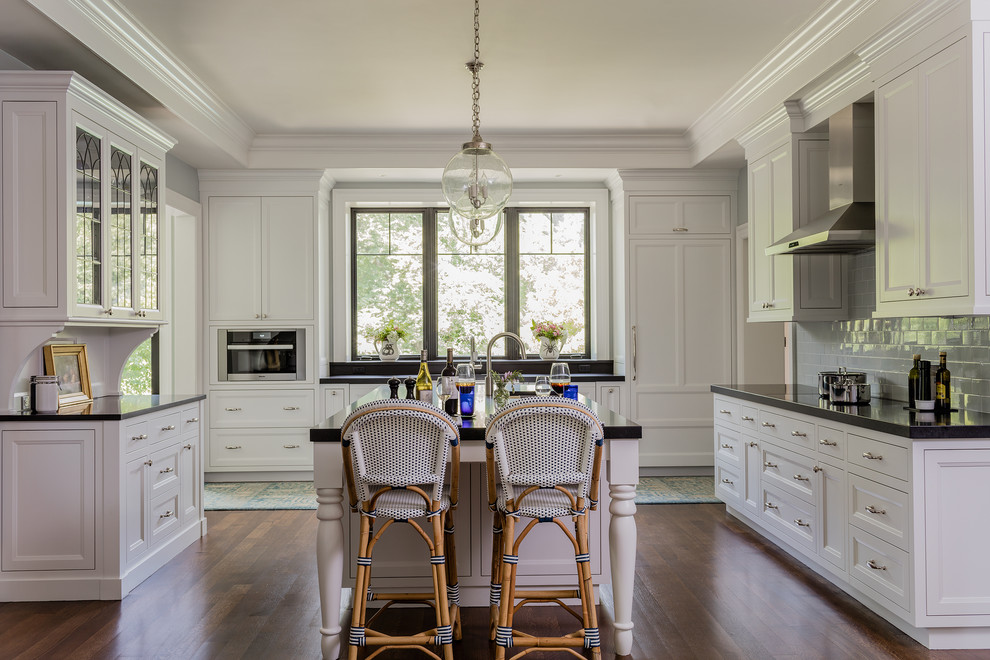 Design ideas for a traditional u-shaped kitchen in Boston with beaded cabinets, white cabinets, blue splashback, metro tiled splashback, stainless steel appliances, dark hardwood flooring, an island and brown floors.