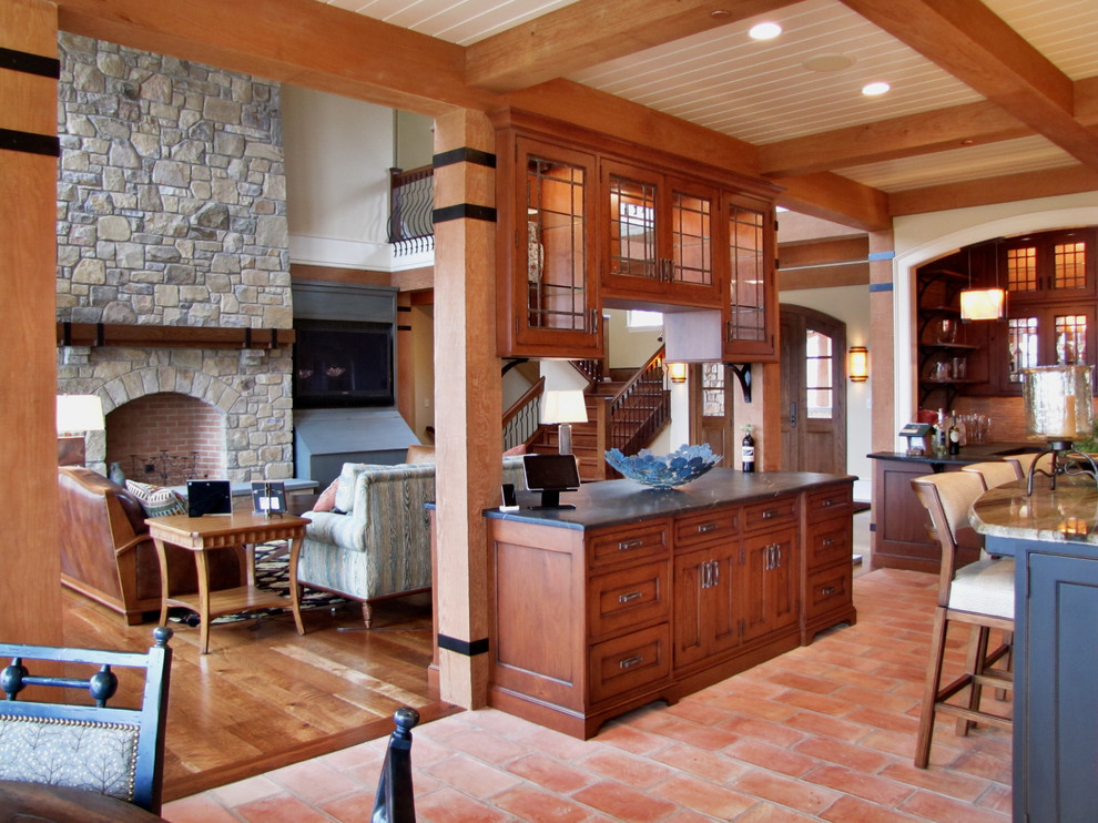 Foto på ett amerikanskt kök med öppen planlösning, med skåp i mellenmörkt trä, granitbänkskiva, stänkskydd i stenkakel, luckor med infälld panel och tegelgolv