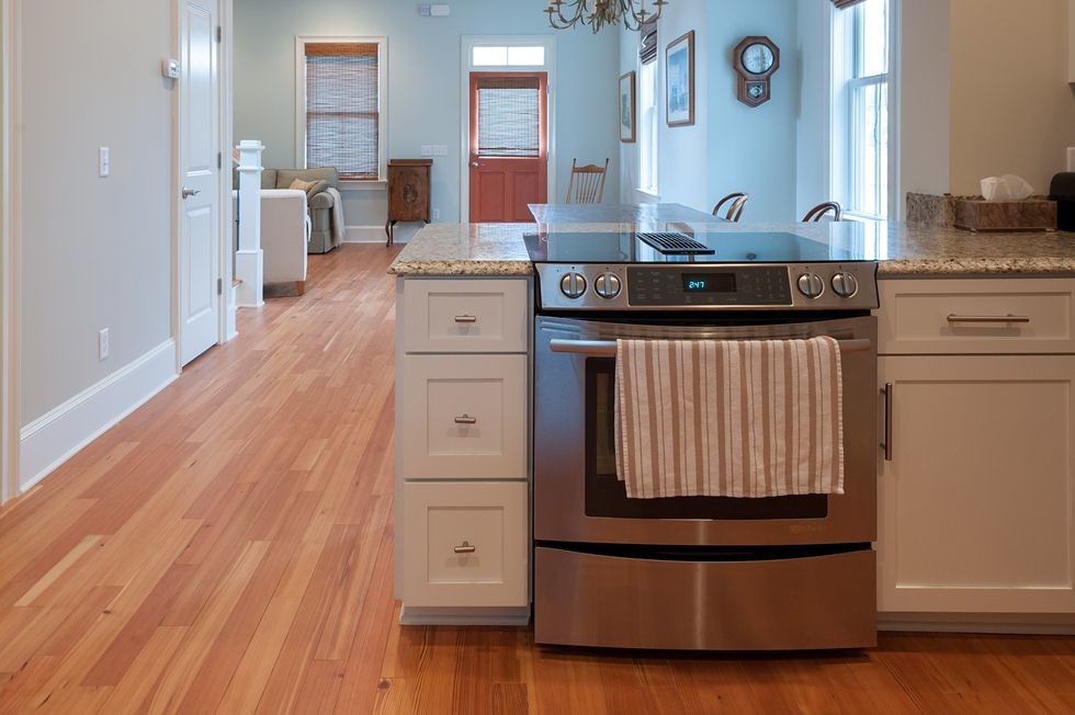 Immagine di una cucina chic di medie dimensioni con ante bianche, top in granito, elettrodomestici in acciaio inossidabile e parquet chiaro