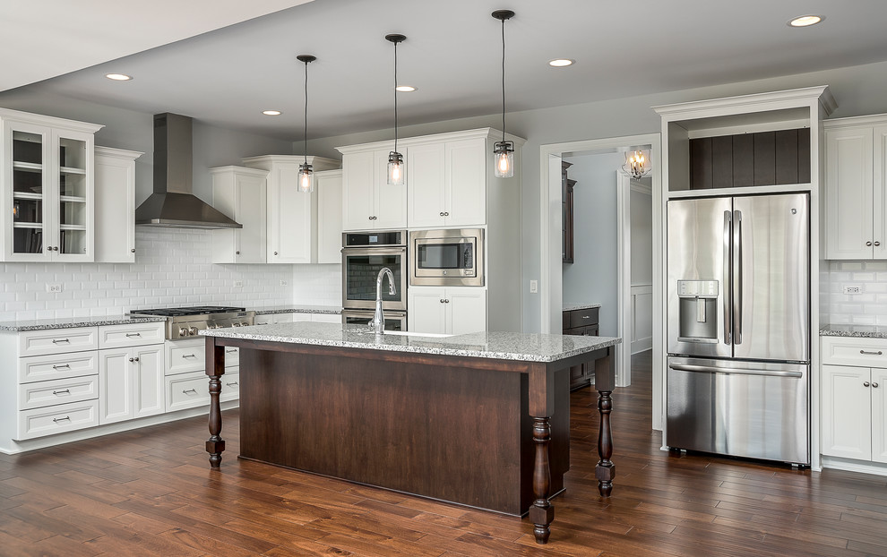 Photo of a large classic l-shaped kitchen/diner in Chicago with a belfast sink, white cabinets, stainless steel appliances, medium hardwood flooring and an island.