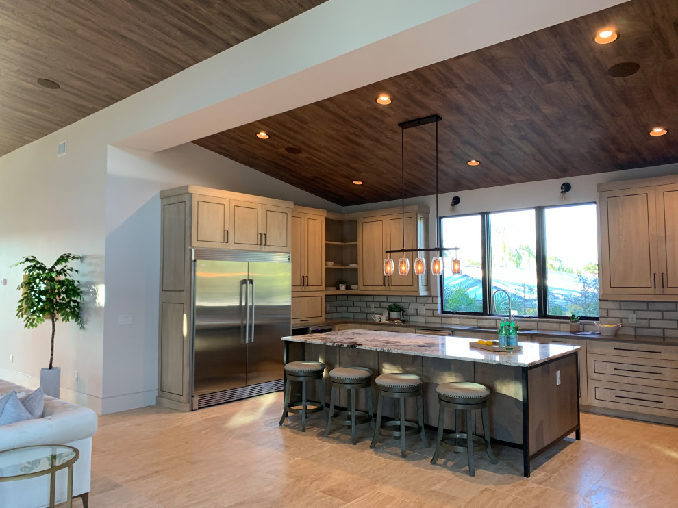 Inspiration for a large mid-century modern u-shaped travertine floor and white floor kitchen remodel in Tampa with an undermount sink, flat-panel cabinets, light wood cabinets, granite countertops, gray backsplash, terra-cotta backsplash, stainless steel appliances, an island and beige countertops