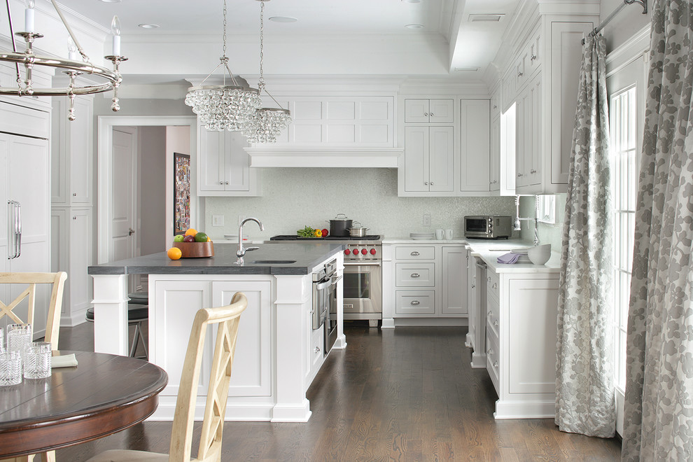 Klassische Wohnküche in U-Form mit Schrankfronten im Shaker-Stil, weißen Schränken, Küchenrückwand in Weiß, Küchengeräten aus Edelstahl, dunklem Holzboden und Kücheninsel in New York