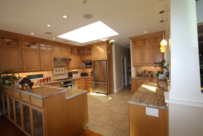 Exempel på ett eklektiskt kök, med en undermonterad diskho, luckor med upphöjd panel, skåp i ljust trä, granitbänkskiva, beige stänkskydd, stänkskydd i stenkakel, rostfria vitvaror och klinkergolv i porslin