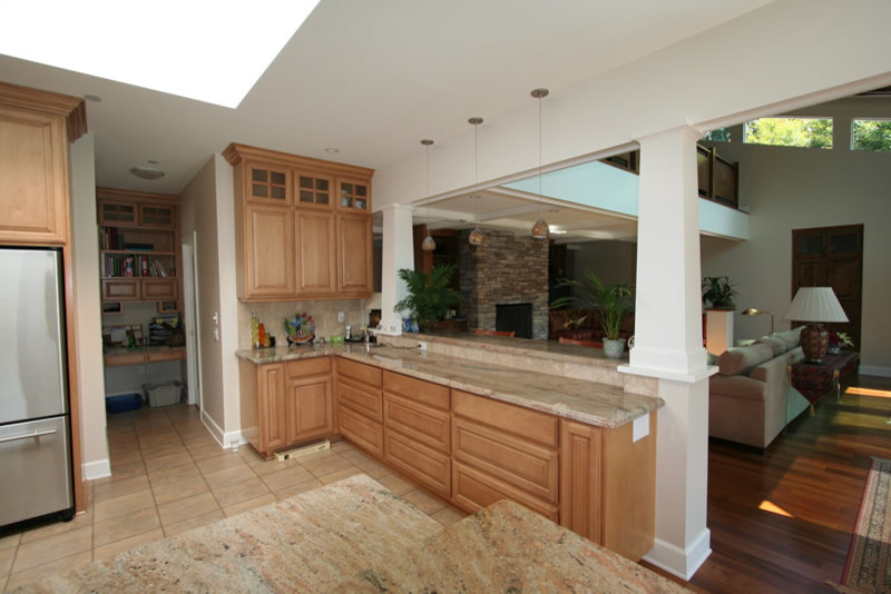 Example of an eclectic u-shaped porcelain tile open concept kitchen design in Los Angeles with an undermount sink, raised-panel cabinets, light wood cabinets, granite countertops, beige backsplash, stone tile backsplash and stainless steel appliances