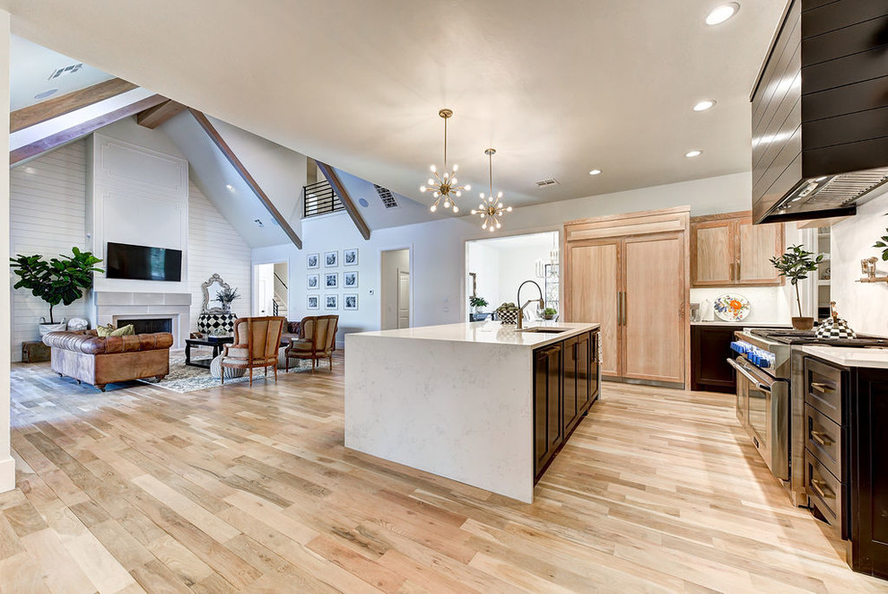 Large transitional l-shaped light wood floor and beige floor open concept kitchen photo in Oklahoma City with an undermount sink, shaker cabinets, light wood cabinets, quartz countertops, white backsplash, paneled appliances, an island and white countertops