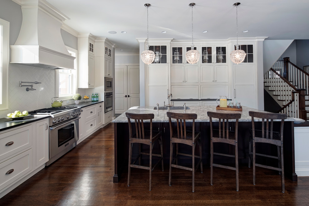 Klassisk inredning av ett kök, med en undermonterad diskho, luckor med profilerade fronter, vita skåp, granitbänkskiva, vitt stänkskydd, stänkskydd i keramik och integrerade vitvaror