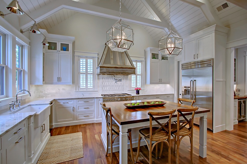 Bild på ett stort lantligt kök, med en undermonterad diskho, skåp i shakerstil, vita skåp, träbänkskiva, flerfärgad stänkskydd, stänkskydd i mosaik, rostfria vitvaror, mellanmörkt trägolv och en köksö