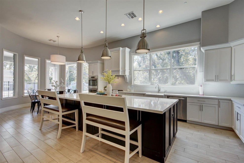 Eat-in kitchen - large transitional l-shaped plywood floor eat-in kitchen idea in Phoenix with shaker cabinets, white cabinets, white backsplash, ceramic backsplash, stainless steel appliances, an island and quartz countertops