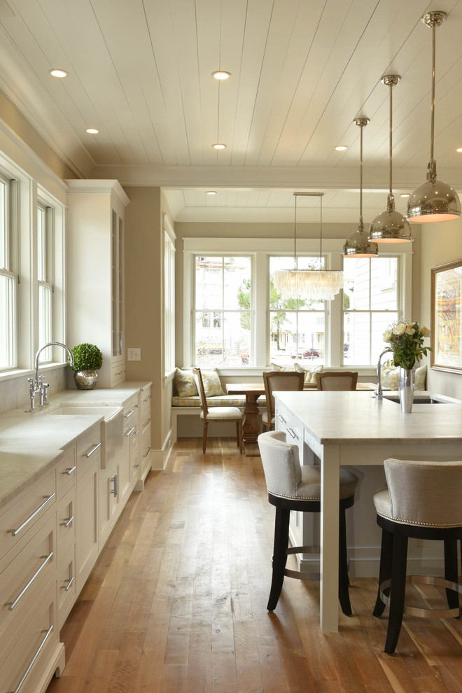Large transitional galley medium tone wood floor and brown floor open concept kitchen photo in Charleston with flat-panel cabinets, white cabinets, marble countertops, gray backsplash, subway tile backsplash, stainless steel appliances, an island and a farmhouse sink