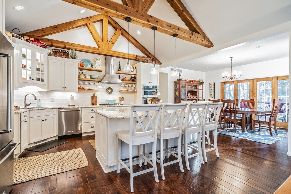 Inspiration for a large country l-shaped medium tone wood floor eat-in kitchen remodel in New York with an undermount sink, shaker cabinets, white cabinets, quartz countertops, white backsplash, subway tile backsplash, stainless steel appliances and an island