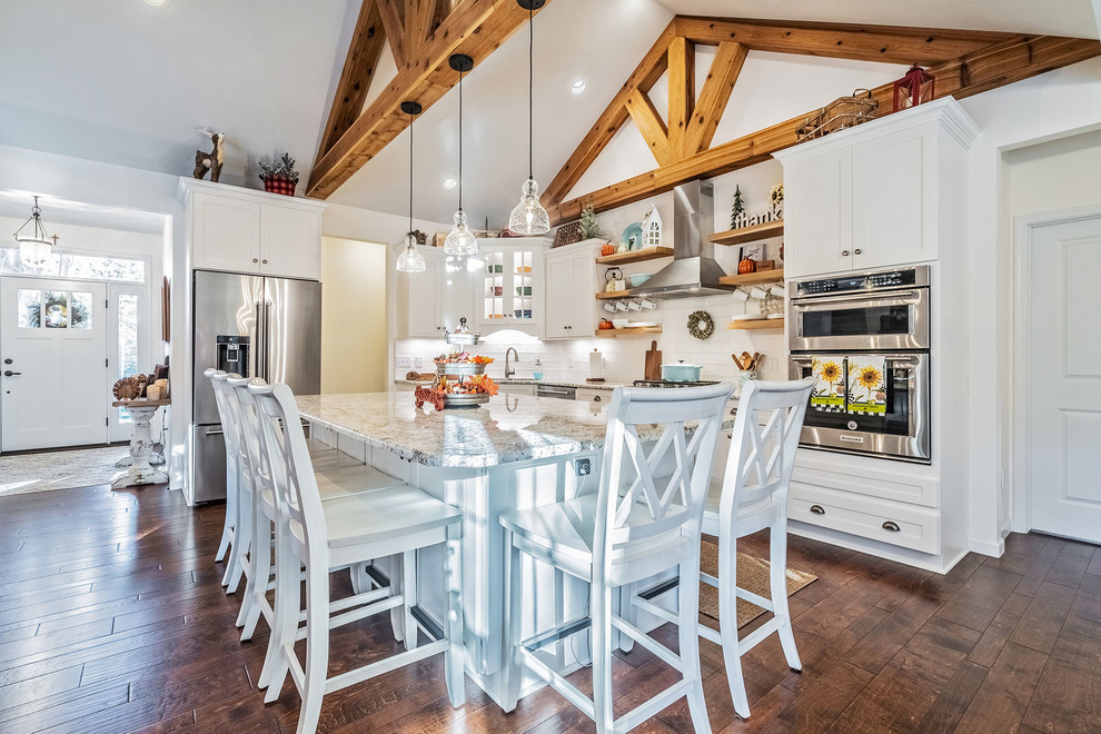 Inspiration for a large country l-shaped medium tone wood floor eat-in kitchen remodel in New York with an undermount sink, shaker cabinets, white cabinets, quartz countertops, white backsplash, subway tile backsplash, stainless steel appliances and an island
