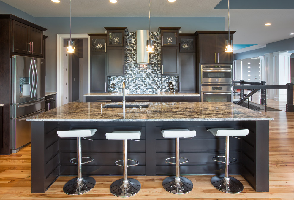 Example of a transitional light wood floor and beige floor kitchen design in Columbus with an undermount sink, shaker cabinets, dark wood cabinets, multicolored backsplash, mosaic tile backsplash, stainless steel appliances and an island