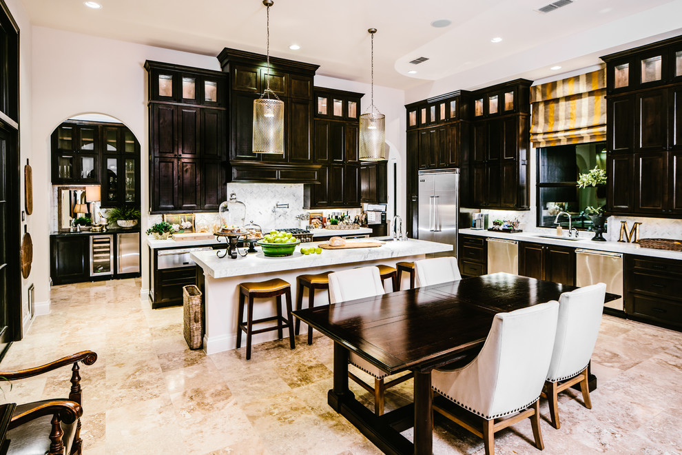 Inspiration for a large transitional l-shaped travertine floor and beige floor eat-in kitchen remodel in Austin with an undermount sink, recessed-panel cabinets, dark wood cabinets, granite countertops, gray backsplash, stainless steel appliances, stone slab backsplash and an island