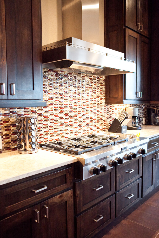 Immagine di una cucina tradizionale con lavello da incasso, ante in legno bruno, paraspruzzi multicolore, elettrodomestici in acciaio inossidabile, ante con riquadro incassato e pavimento con piastrelle in ceramica