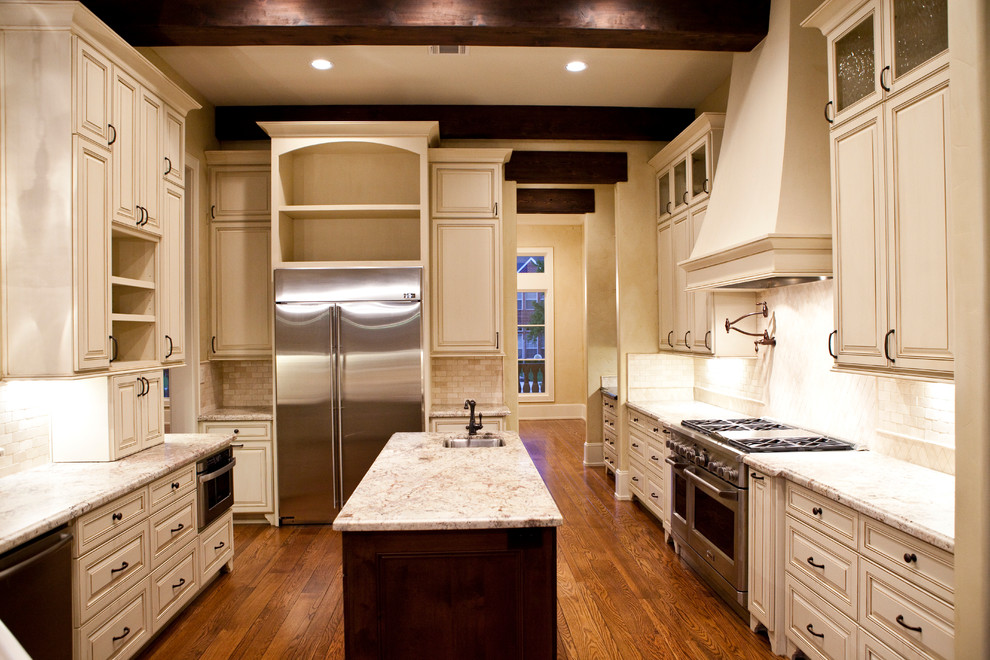 Example of a large mountain style medium tone wood floor kitchen design in Houston with an undermount sink, distressed cabinets, granite countertops, stone tile backsplash, stainless steel appliances and an island