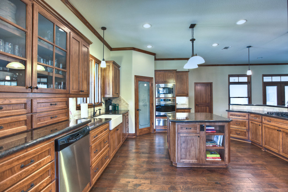 Bild på ett stort rustikt kök, med en rustik diskho, luckor med upphöjd panel, skåp i mellenmörkt trä, granitbänkskiva, beige stänkskydd, rostfria vitvaror, stänkskydd i keramik, mörkt trägolv och en köksö