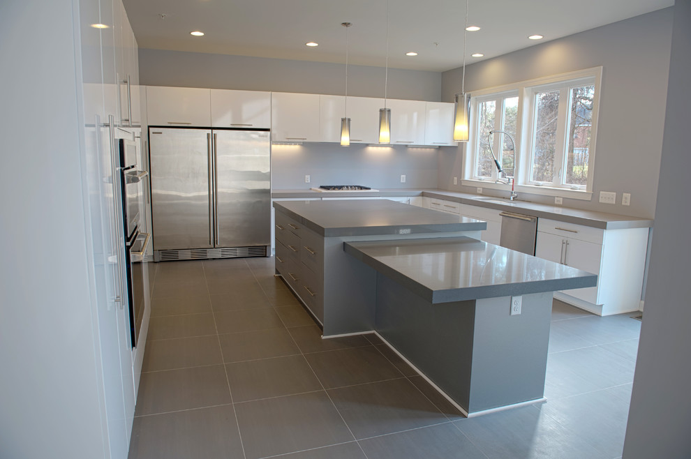 Foto på ett mycket stort funkis kök, med en undermonterad diskho, släta luckor, vita skåp, bänkskiva i kvartsit, grått stänkskydd, rostfria vitvaror och skiffergolv