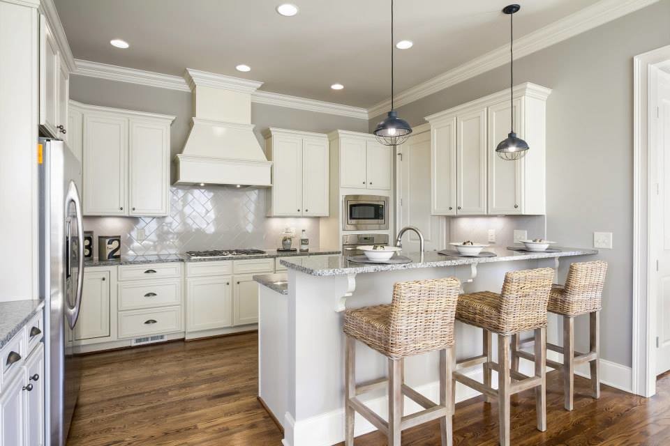Inspiration for a medium sized classic galley enclosed kitchen in Nashville with a built-in sink, raised-panel cabinets, white cabinets, granite worktops, white splashback, terracotta splashback, stainless steel appliances, light hardwood flooring and a breakfast bar.