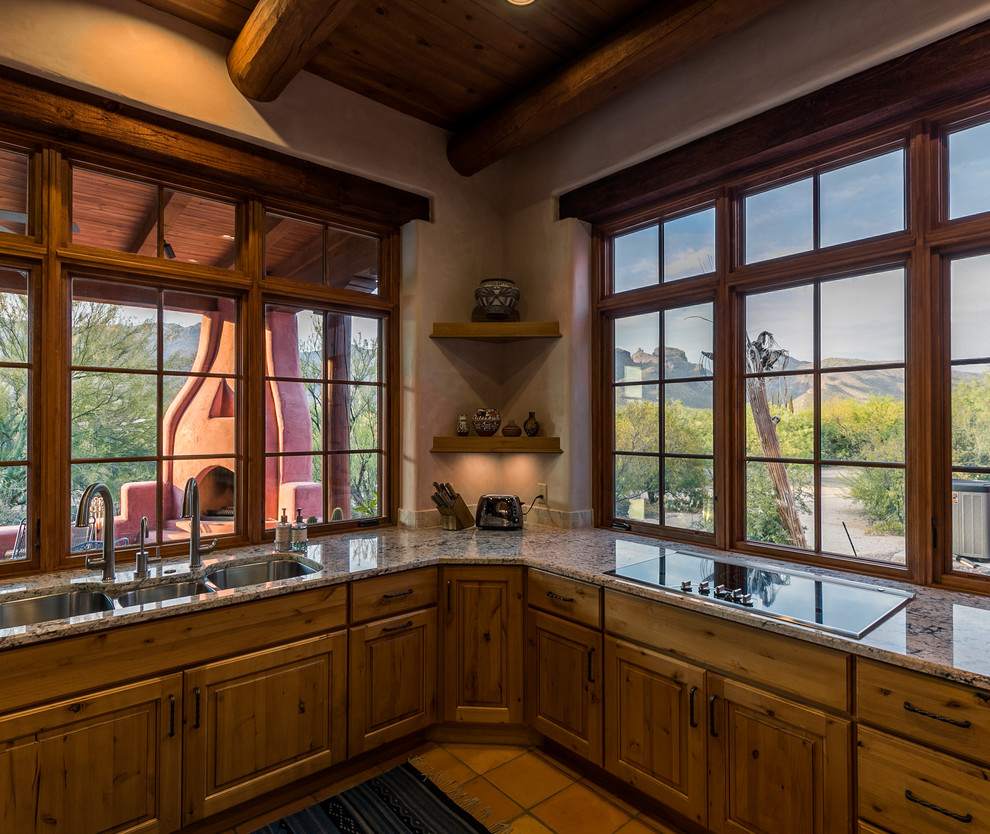 Inspiration for a southwestern terra-cotta tile and pink floor enclosed kitchen remodel in Other with a triple-bowl sink, recessed-panel cabinets, brown cabinets, granite countertops, stainless steel appliances and no island