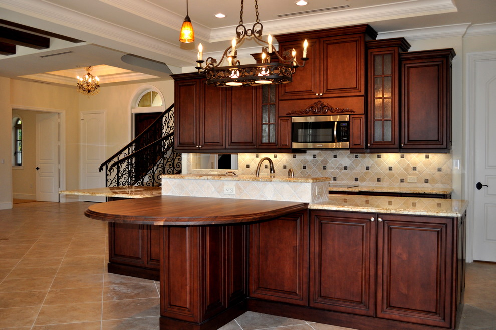 Foto på ett stort medelhavsstil kök och matrum, med en undermonterad diskho, luckor med upphöjd panel, skåp i mellenmörkt trä, granitbänkskiva, beige stänkskydd, stänkskydd i stenkakel, rostfria vitvaror, klinkergolv i porslin och en köksö