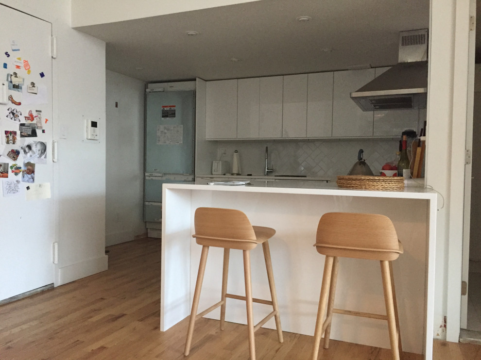 Immagine di una piccola cucina moderna con ante lisce, ante gialle, paraspruzzi con piastrelle di vetro, pavimento in laminato, penisola e pavimento beige