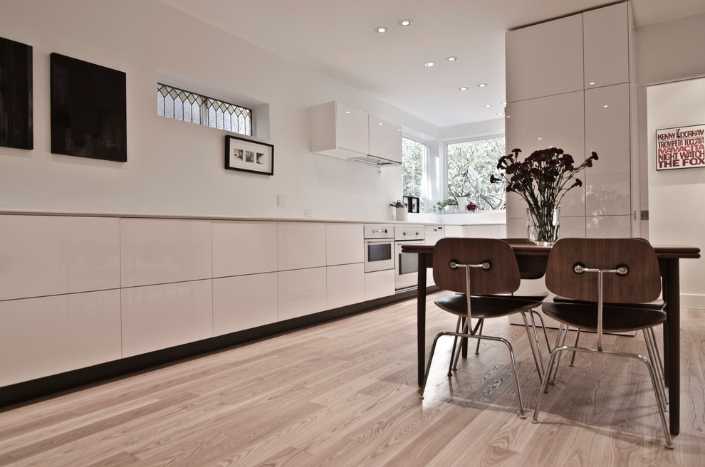 Стильный дизайн: кухня-гостиная в стиле модернизм с врезной мойкой, плоскими фасадами, белыми фасадами и столешницей из кварцевого агломерата - последний тренд