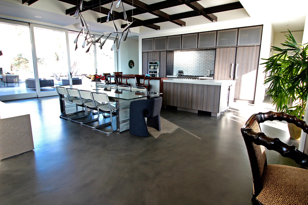 サンディエゴにあるモダンスタイルのおしゃれなキッチン (フラットパネル扉のキャビネット、茶色いキャビネット、珪岩カウンター、白いキッチンパネル、サブウェイタイルのキッチンパネル、シルバーの調理設備、コンクリートの床) の写真