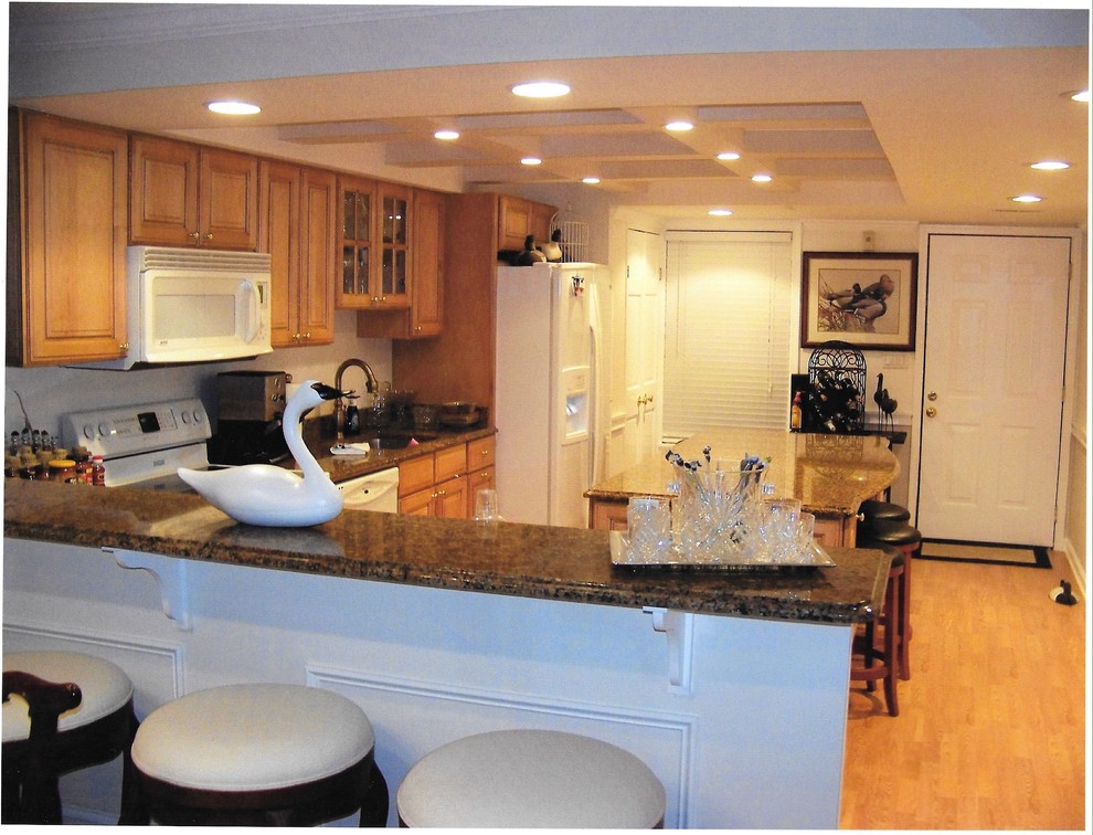Foto på ett funkis kök, med en köksö, luckor med upphöjd panel, skåp i mellenmörkt trä, granitbänkskiva, vita vitvaror, en undermonterad diskho och ljust trägolv