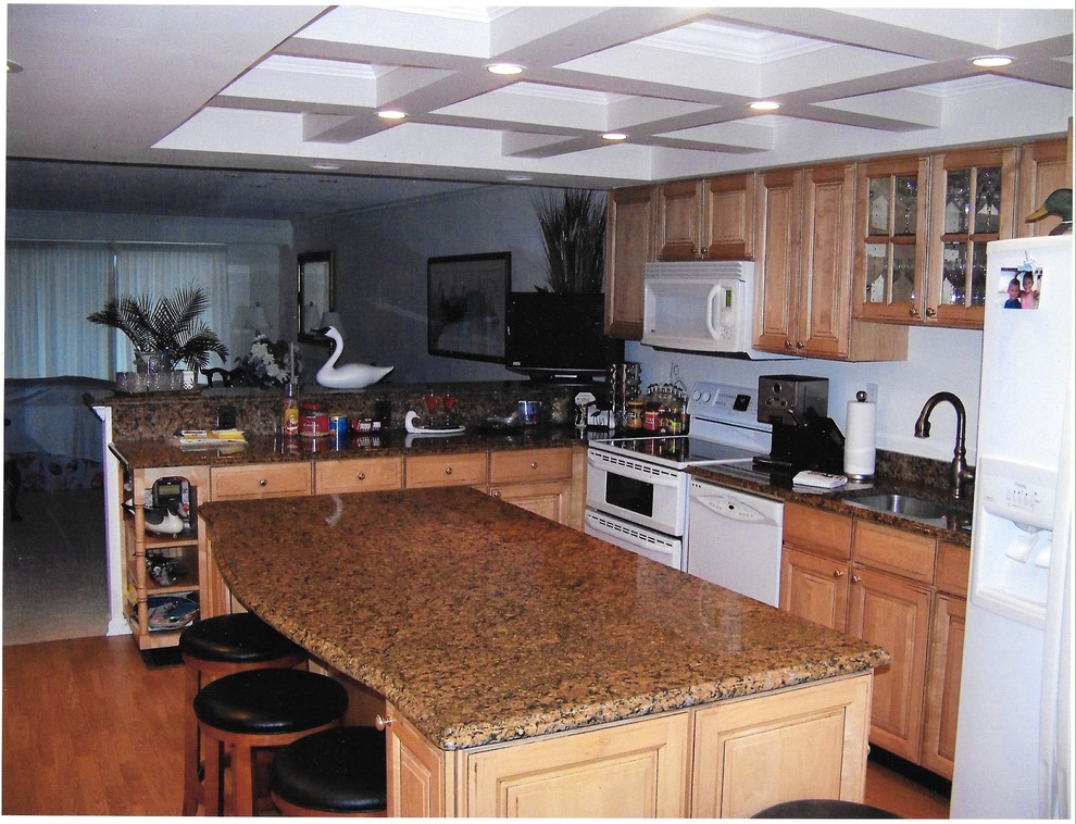 Inspiration for a contemporary l-shaped light wood floor eat-in kitchen remodel in Baltimore with an island, raised-panel cabinets, medium tone wood cabinets, granite countertops, white appliances and an undermount sink