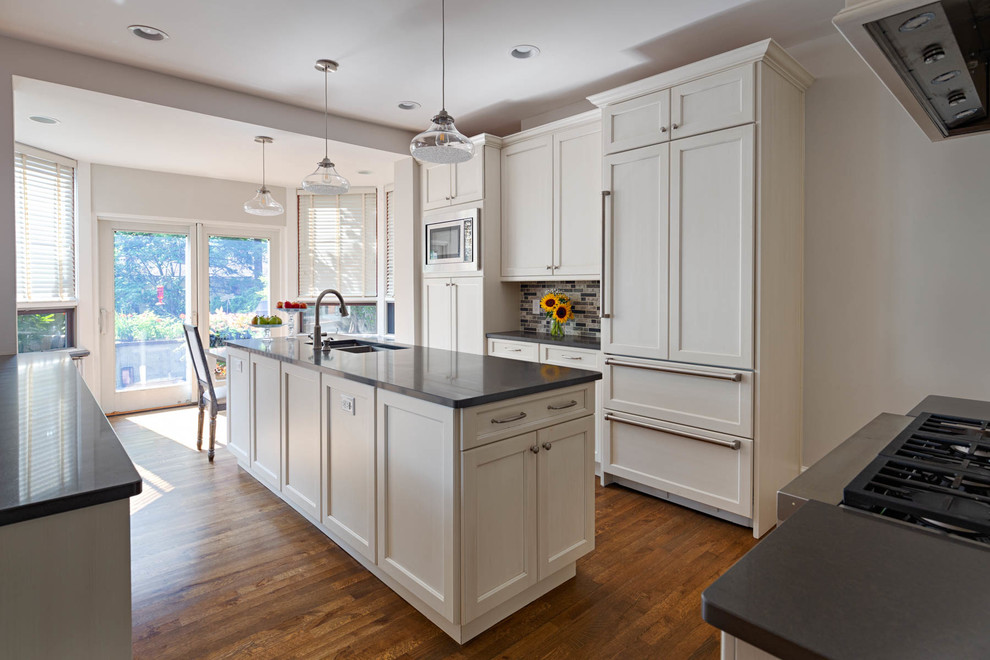 Example of a kitchen design in Other with white cabinets, an island and black countertops