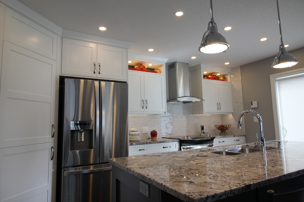 Example of a trendy dark wood floor kitchen design in Vancouver with an undermount sink, shaker cabinets, white cabinets, granite countertops, white backsplash, mosaic tile backsplash, stainless steel appliances and an island