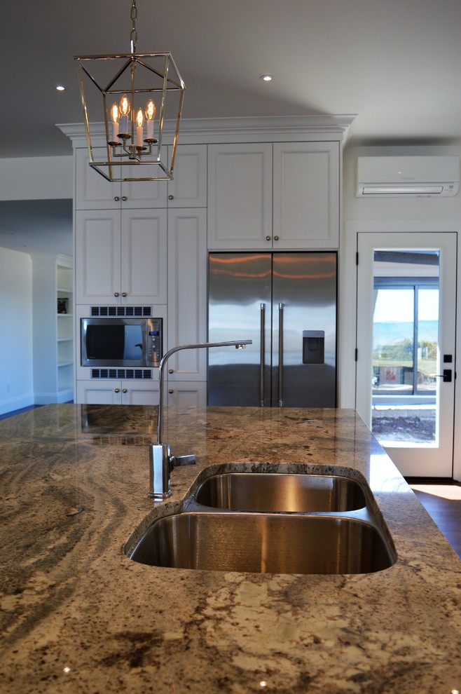 Exempel på ett mycket stort klassiskt flerfärgad flerfärgat kök, med en undermonterad diskho, skåp i shakerstil, vita skåp, granitbänkskiva, vitt stänkskydd, stänkskydd i keramik, rostfria vitvaror, mörkt trägolv, en köksö och brunt golv