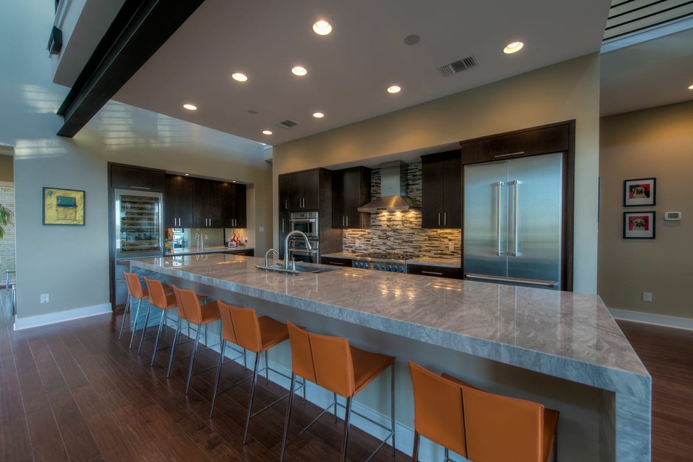 Photo of a large modern l-shaped enclosed kitchen in Austin with a belfast sink, flat-panel cabinets, dark wood cabinets, composite countertops, multi-coloured splashback, stainless steel appliances, medium hardwood flooring and an island.