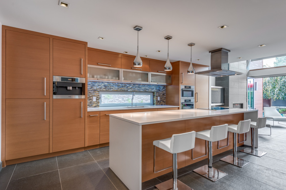 Contemporary kitchen in Vancouver with a built-in sink, flat-panel cabinets, medium wood cabinets, marble worktops, multi-coloured splashback, ceramic splashback, stainless steel appliances, ceramic flooring, an island, grey floors and white worktops.