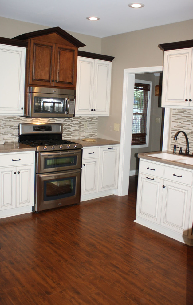 Klassisk inredning av ett kök, med en undermonterad diskho, luckor med upphöjd panel, bänkskiva i koppar, stänkskydd i glaskakel, rostfria vitvaror, mellanmörkt trägolv och en halv köksö