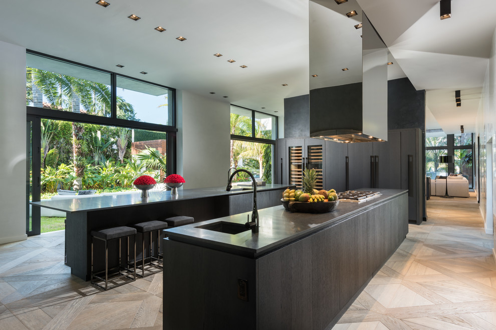 Moderne Küchenbar mit Waschbecken, flächenbündigen Schrankfronten, dunklen Holzschränken, Elektrogeräten mit Frontblende, hellem Holzboden und zwei Kücheninseln in Miami